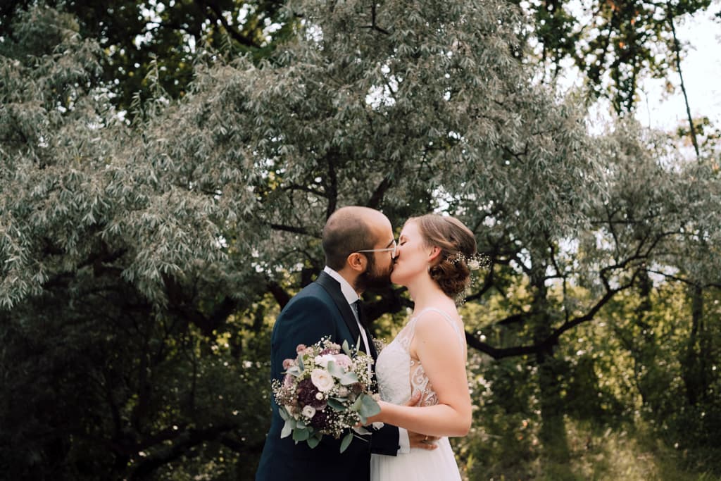 Bride and groom passionately kissing in the garden of Seestern Britzer Garten