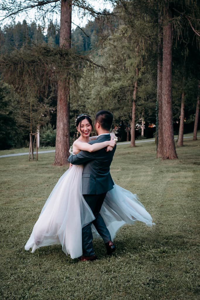 Groom carries bride in the park of a mansion at lake Bled in Slovenia