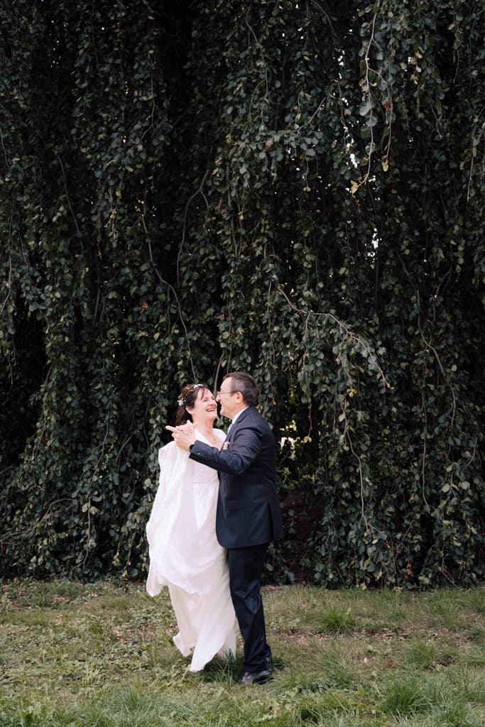 bride and groom laughing and dancing in front of a tree in Schloss Lübbenau in Spreewald